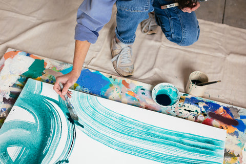 A closeup of Eva's hand as she paints teal, abstract arches