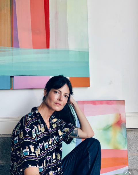 Eva in her studio with two original paintings behind her